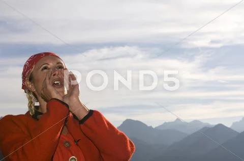Young woman in mountains shouting, low angle view, portrait Stock Photos
