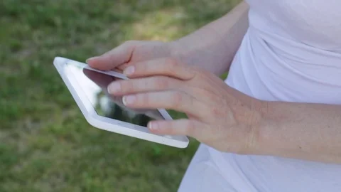 Young woman multitasking on tablet computer with green grass background, ou.. Stock Footage 72338122