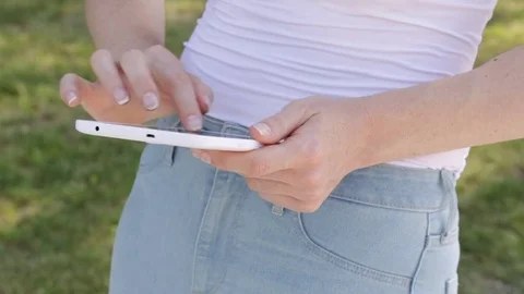 Young woman multitasking on tablet computer with green grass background Stock Footage 72348170