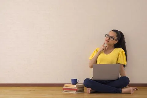 A young woman musing while working on her laptop. Stock Photos