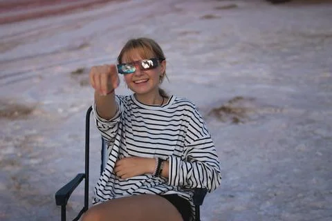 Young woman observing a solar eclipse through safety glasses, smiling happi.. Stock Photos