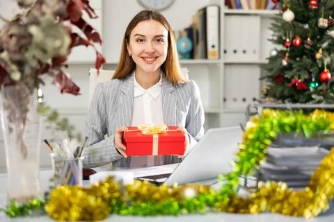 Young woman office worker with gift box during Christmastime Stock Photos
