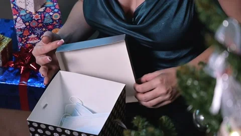 Young woman opens a gift box with medical masks inside while sitting near a Stock Footage 166095951