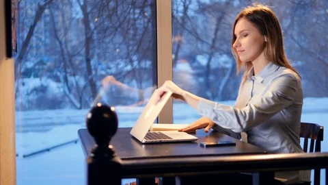 Young woman opens the laptop computer and starts typing near panoramic window Stock Footage 81662467