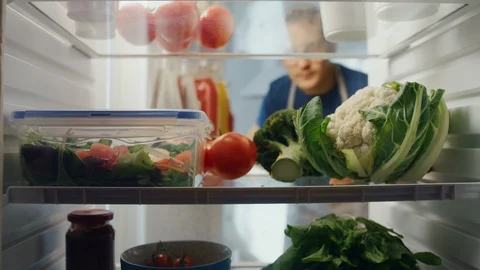 Young Woman Opens Refrigerator Full of Food and Grabs a Bunch of Vegetables Stock Footage 128496943
