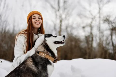 Young woman outdoors in a field in winter walking with a dog fresh air Stock Photos