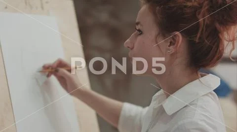 Young woman painter making sketches on blank canvas in artist workshop Stock Photos