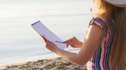 Young woman is painting on the beach Stock Footage