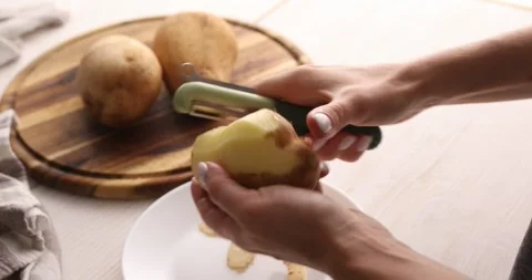 A young woman peels potatoes. The process of food preparation. Stock Footage 249100749