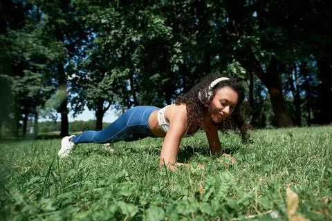 Young woman performing a plank exercise in the park. Stock Photos