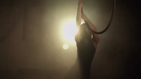 Young woman performs the acrobatic elements in the air hoop. Aerialist in on Stock Footage 233450757