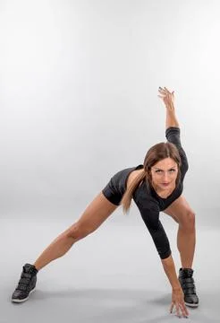 Young woman performs dynamic stretch pose Stock Photos