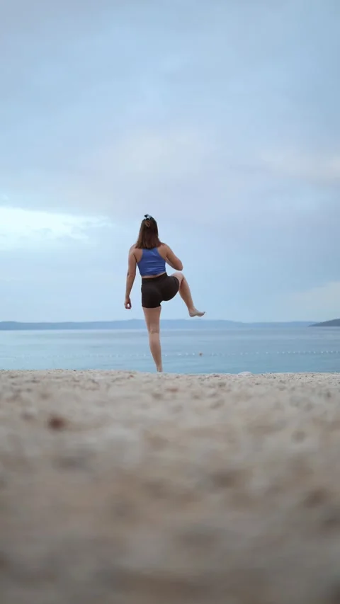 Young woman performs dynamic warm up on a beach Stock Footage 341317913