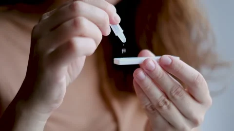 A young woman performs a self-test for Covid-19 antigen at home. Dripping soluti Stock Footage 164618385