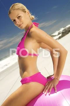 Young Woman In Pink Bikini On The Beach, Sitting On A Large Ball