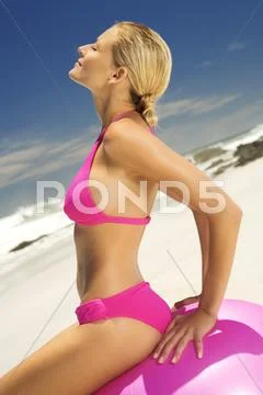 Young Woman In Pink Bikini On The Beach, Sitting On A Large Ball