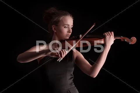 Young woman playing violin on black background Stock Photos