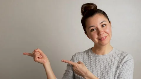 Young woman pointing to empty space on grey background Stock Footage 238355708