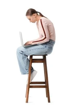Young woman with poor posture using laptop on stool against white background Stock Photos