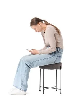 Young woman with poor posture using mobile phone on stool against white backg Stock Photos