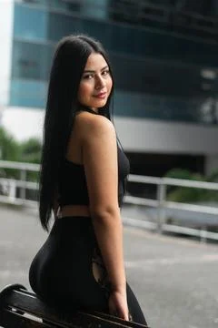 Young woman posing from back angle near city railing in contemporary street.. Stock Photos