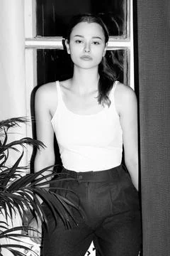Young woman posing casually by window indoors Stock Photos