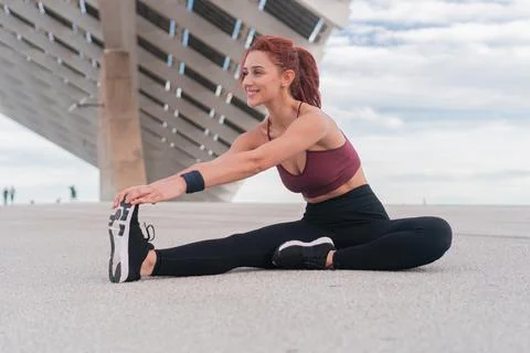 Young woman posing while working out, getting fit and stretching leg sitting and Stock Photos