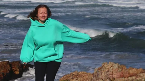 Young Woman Posing in Wind by the Ocean Shore Stock Footage 310952653