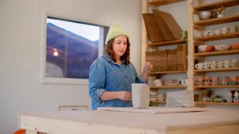Young woman in pottery studio using wire clay cutters to cut clay pieces 库存影片 221949572