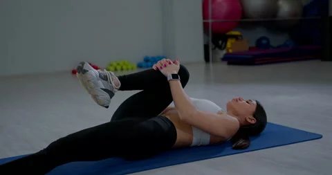 Young woman practices Single Knee to Chest stretch and Supine Spinal Twist Stock Footage 328961142