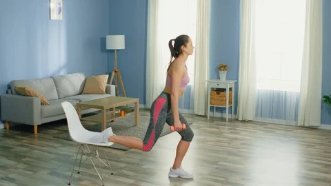 Young Woman Practices Split Squat Using Chair Stock Footage 128428832