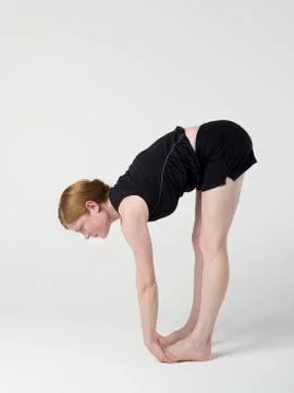 A young woman practicing the 'Upward Forward Fold' yoga pose Stock Photos