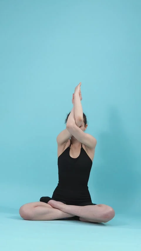 Young Woman Practicing Yoga Eagle Arms Pose on Blue Background Stock Footage 344782489
