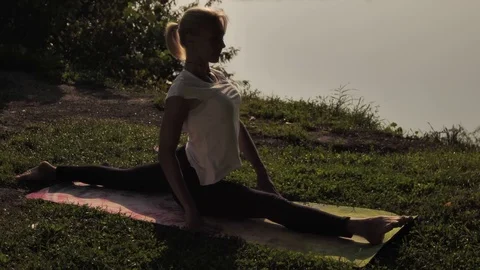 Young woman practicing yoga at sunset outdoors Stock Footage