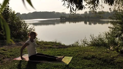 Young woman practicing yoga at sunset outdoors Stock Footage