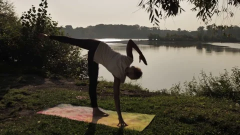 Young woman practicing yoga at sunset outdoors Stock Footage