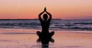 Young Woman Practises Yoga On Beach At Sunset, With Pink Sky Stock Footage