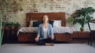 Young Woman Is Practising Yoga At Home Resting In Lotus Pose With Hands On Knees Stock Footage