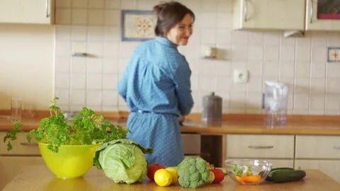 A young woman is preparing a soup dancing between a stove and a table. Great Stock Footage