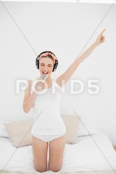 Young woman pretending to sing while listening to music with closed eyes Stock Photos