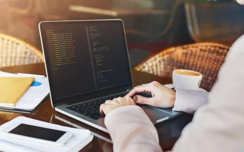 Young woman programmer writing code on laptop in cafe 写真素材