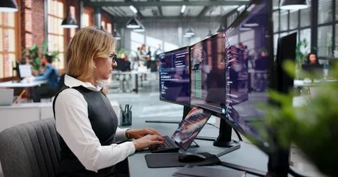 Young Woman Programs Code On Her Laptop In A Bright Office. Fotos Stock