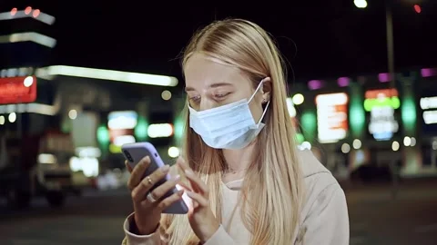 Young woman with protective medical face mask use phone at night city smartphone Stock Footage