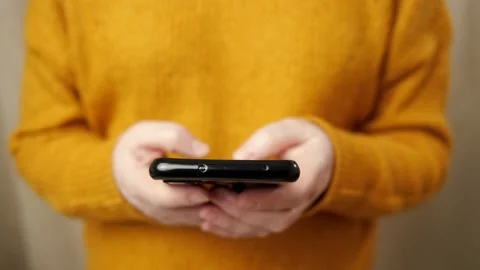Young woman in pullover hands type on black smartphone Stock Footage 147591901