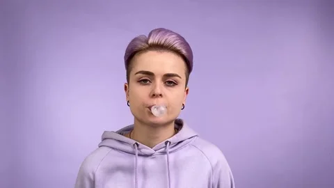 Young woman in purple chewing gum, indifferent look, blowing bubble Stock Footage