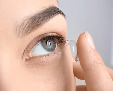 Young woman putting contact lens in her eye, closeup Stock Photos