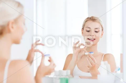 Young woman putting on contact lenses at bathroom Stock Photos