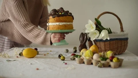 Young woman putting easter cake decorated with chocolate eggs on the table .. Stock Footage 74297911