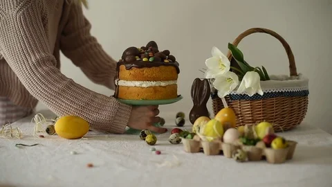 Young woman putting easter cake decorated with chocolate eggs on the table .. Stock Footage 74297954
