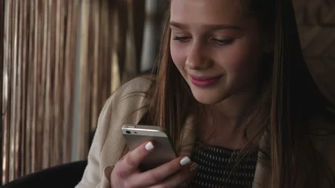 Young woman reading and replying to a message on her mobile phone Stock Footage 166316654